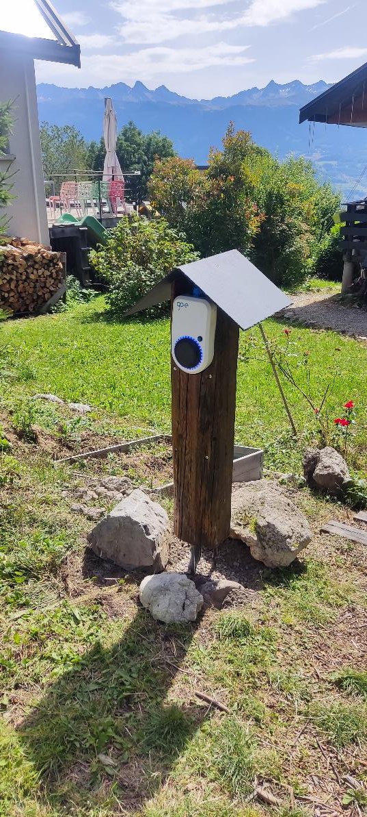Borne de recharge Go-e installée sur un poteau en bois dans le jardin, vue sur les montagnes de Chartreuse
