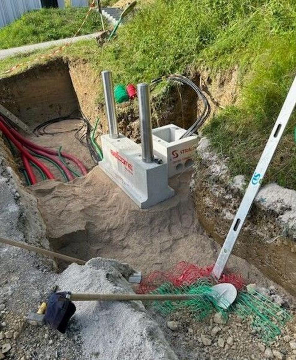 Massif anticollision béton armé avec potelets inox amovibles, en cours de pose sur chantier